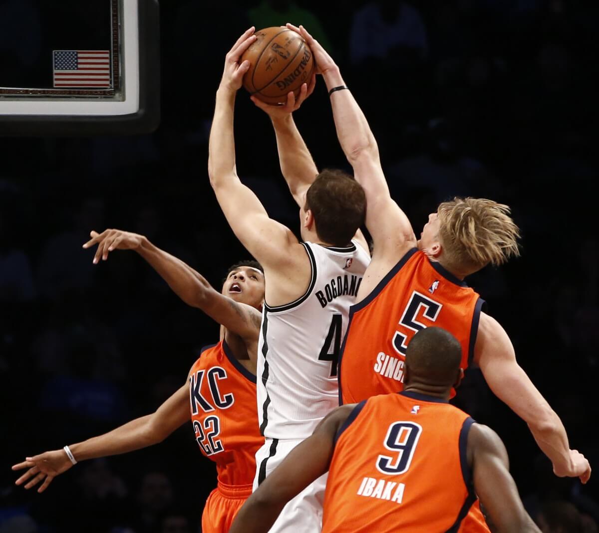 Oklahoma City Thunder forward Kyle Singler (5) and Thunder guard Cameron Payne (22) defend Brooklyn Nets guard Bojan Bogdanovic (44) as Thunder forward Serge Ibaka (9) in the first half of an NBA basketball game, Sunday, Jan. 24, 2016, in New York. (AP Photo/Kathy Willens)