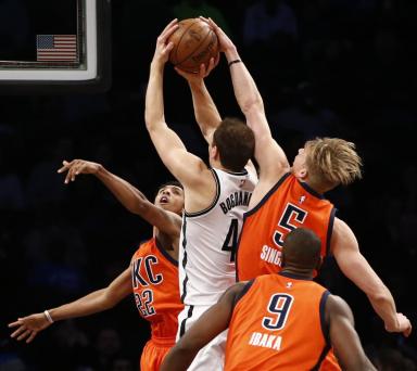 Oklahoma City Thunder forward Kyle Singler (5) and Thunder guard Cameron Payne (22) defend Brooklyn Nets guard Bojan Bogdanovic (44) as Thunder forward Serge Ibaka (9) in the first half of an NBA basketball game, Sunday, Jan. 24, 2016, in New York. (AP Photo/Kathy Willens)