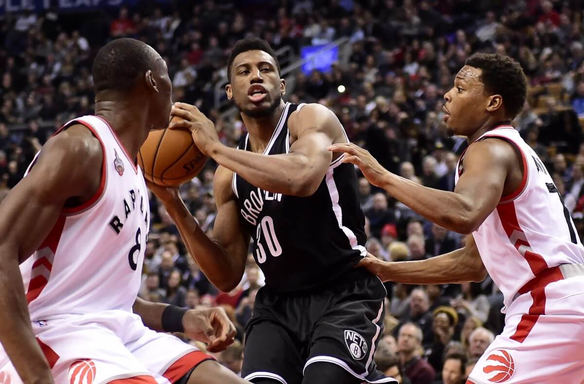 Brooklyn Nets' Thaddeus Young (30) drives to the net as Toronto Raptors' Bismack Biyombo (8) and Kyle Lowry (7) defend during first half NBA basketball action in Toronto, Monday, Jan. 18, 2016. (Frank Gunn/The Canadian Press via AP) MANDATORY CREDIT