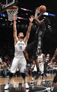 Minnesota Timberwolves guard Andrew Wiggins (22) leaps to the basket past Brooklyn Nets center Brook Lopez (11) during the first half of an NBA basketball game on Sunday, Dec. 20, 2015, in New York. (AP Photo/Kathy Kmonicek)