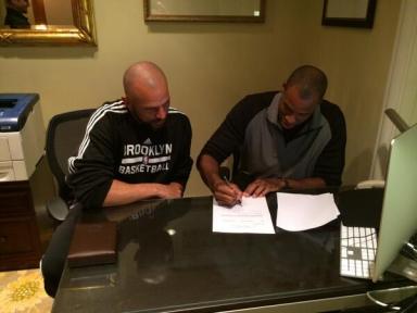 Jason Collins signing his contract with the Brooklyn Nets.